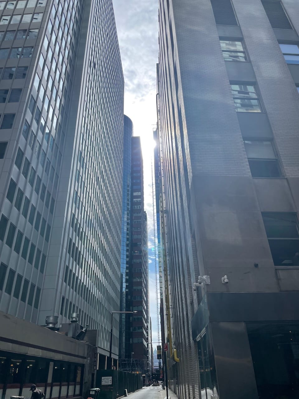 Sun shining through buildings in a New York City skyline.